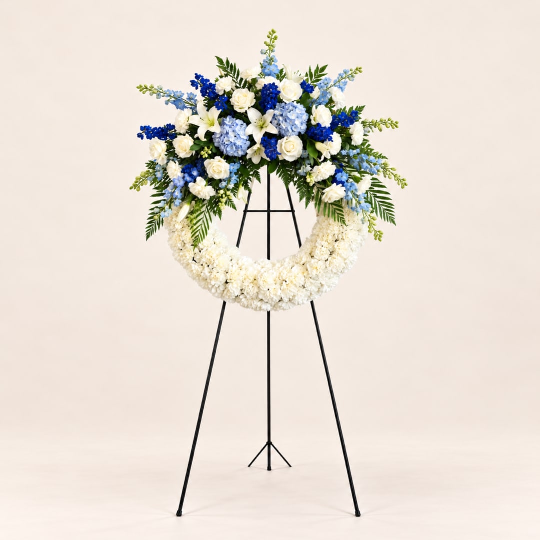 Blue and white floral funeral wreath on a black stand