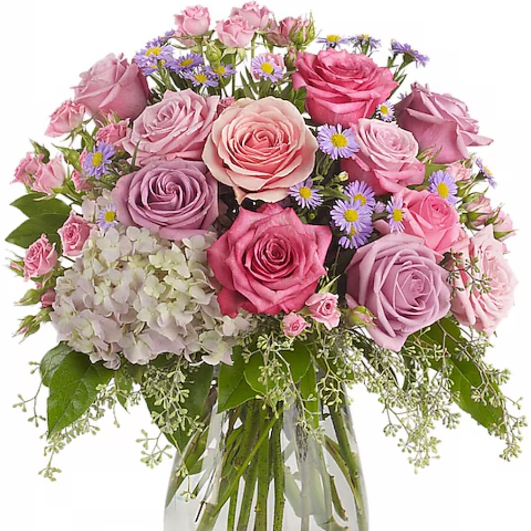 Bouquet of pink and lavender roses with small purple daisies in a glass vase