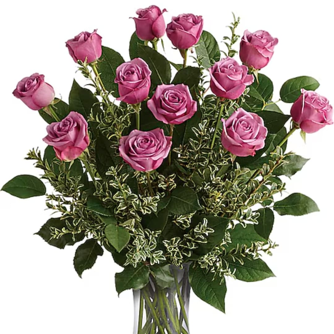 Bouquet of pink roses with mixed greenery in a clear glass vase