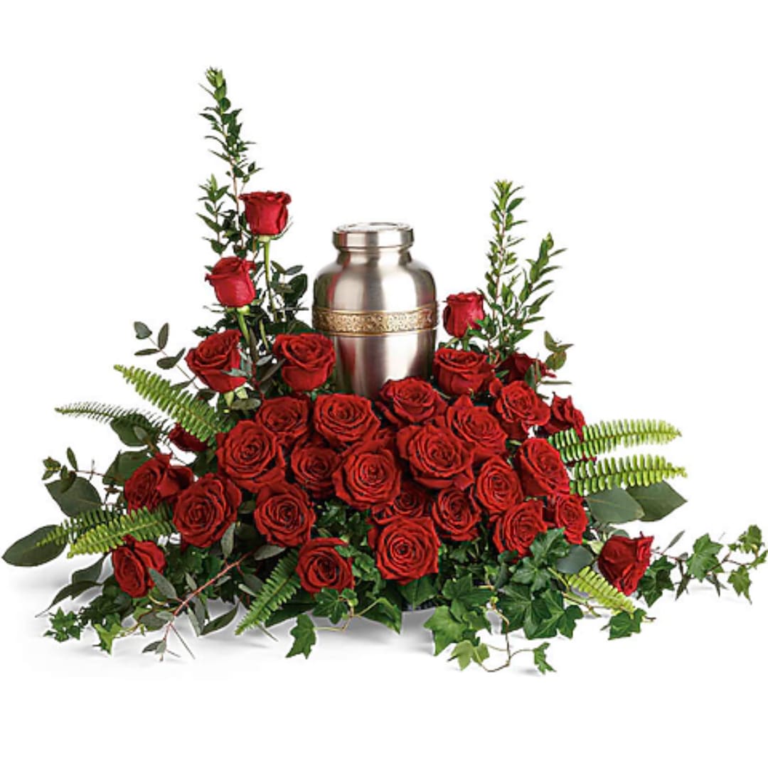 Red roses arranged around a silver urn with greenery