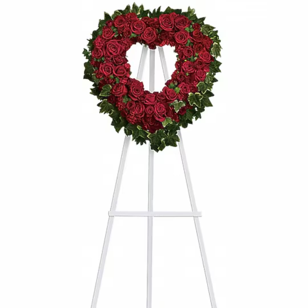 Heart-shaped red rose wreath on a white easel stand