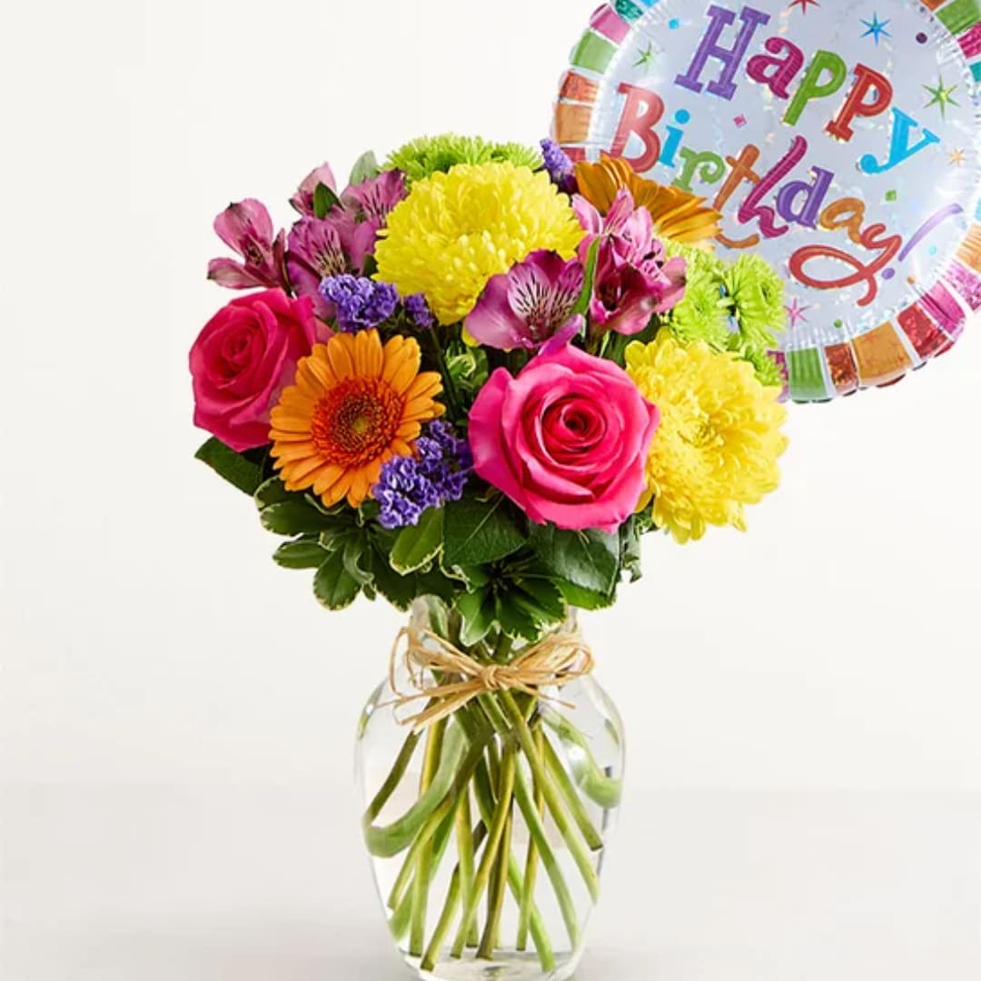 Colorful bouquet in a glass vase with a birthday balloon