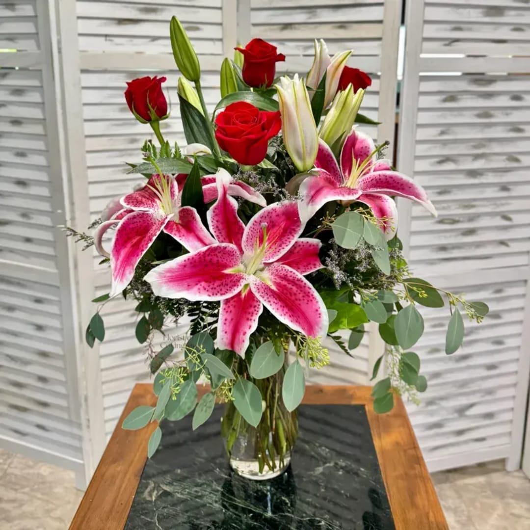 Bouquet of pink lilies and red roses in a clear glass vase