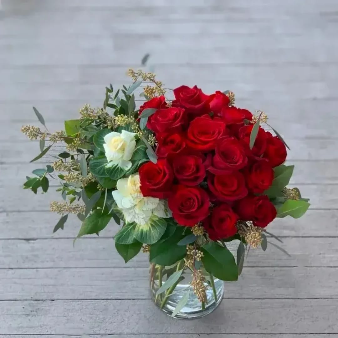 Red roses and white blooms arranged in a clear glass vase