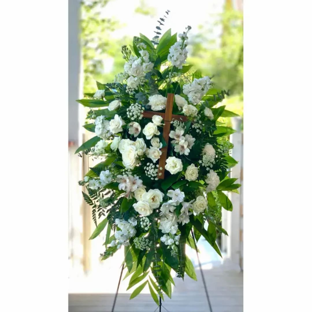 White floral standing spray on an easel with green foliage