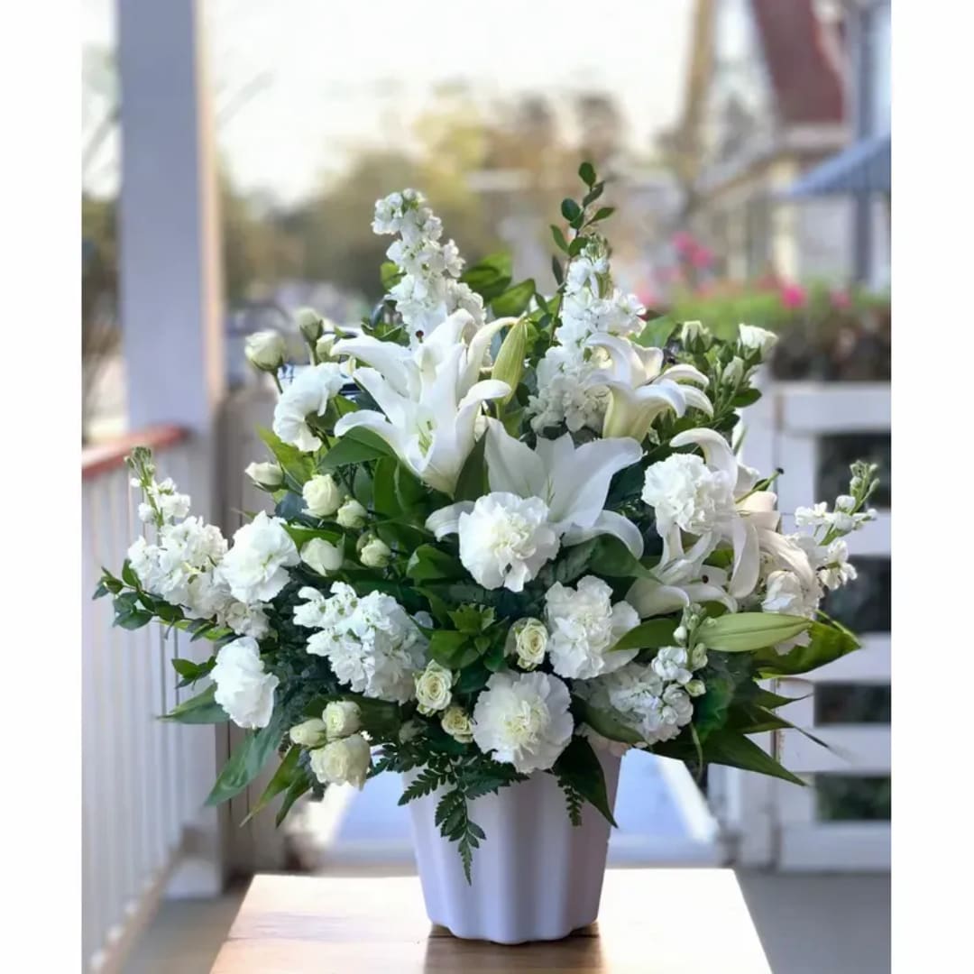 White lilies and carnations arranged in a white vase