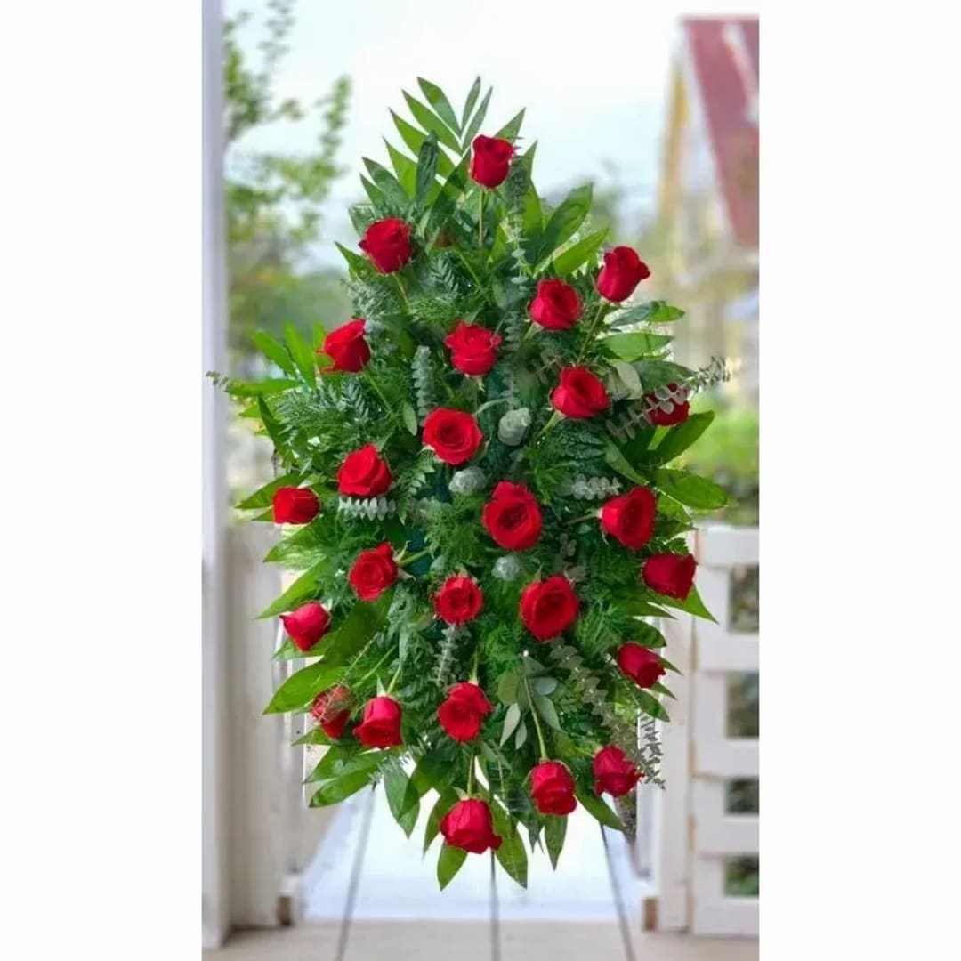 Tall standing spray of red roses and greenery on an easel