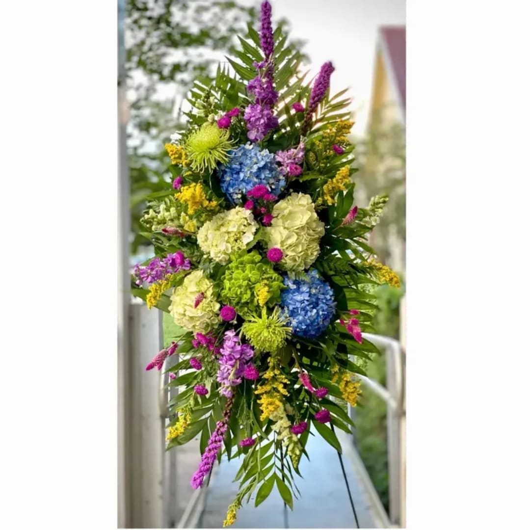 Tall colorful floral arrangement with blue, green, purple, and yellow blooms