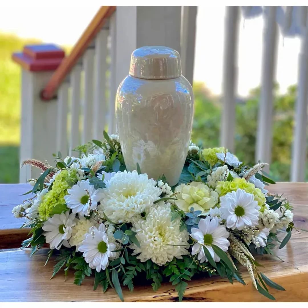 White urn surrounded by white and pale green flowers on a table