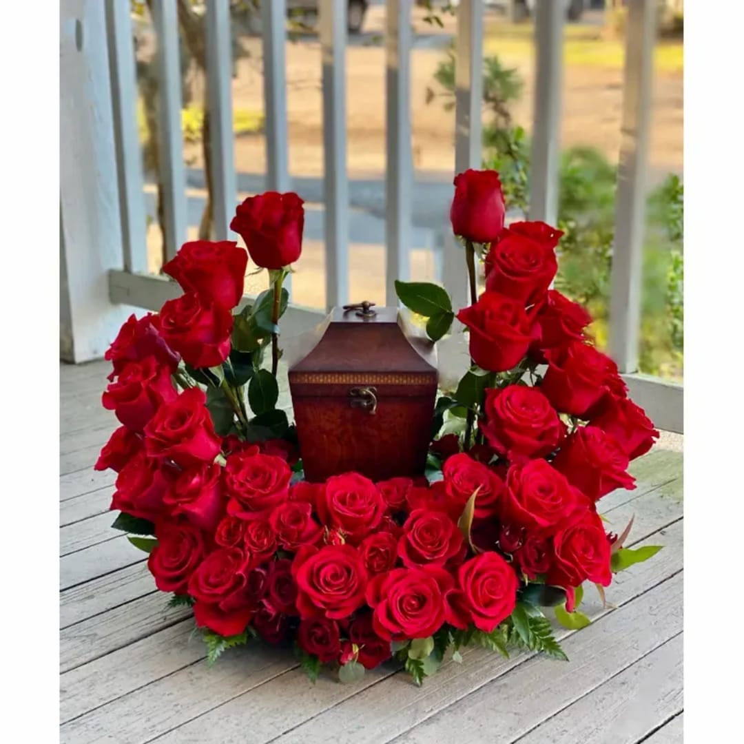 Red rose wreath around a small wooden box on a porch