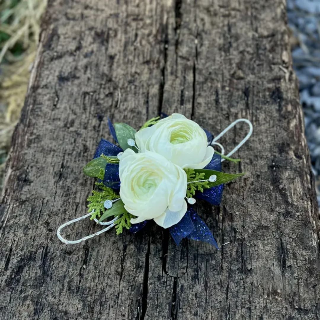White ranunculus boutonniere with blue ribbon on weathered wood