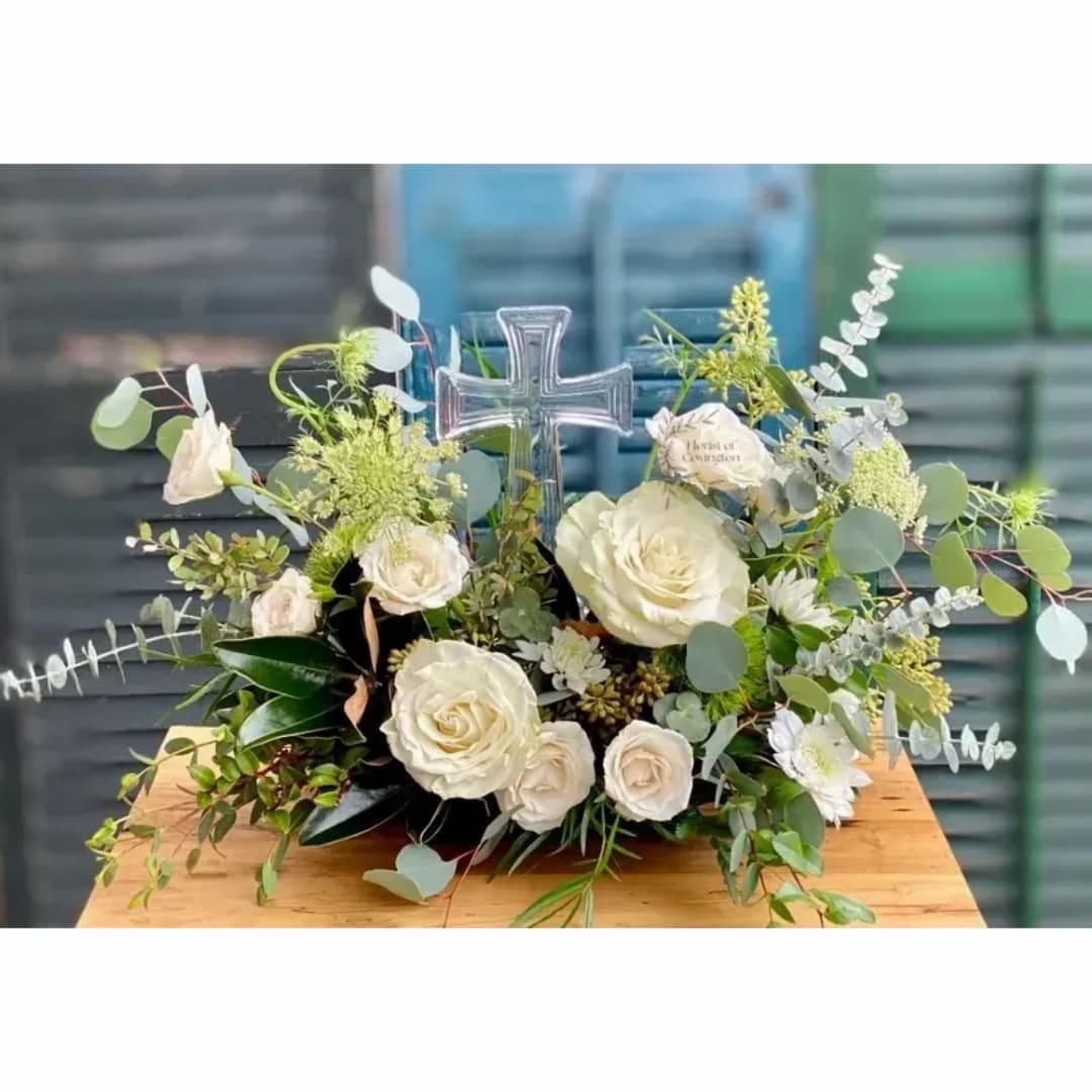 White roses arranged around a clear cross centerpiece