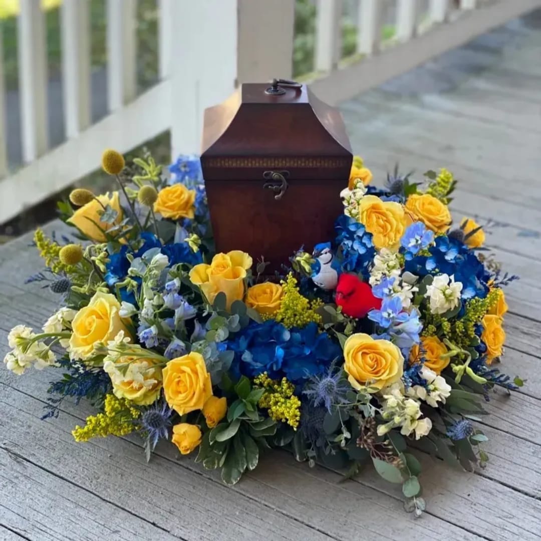 Yellow roses and blue flowers arranged around a wooden keepsake box
