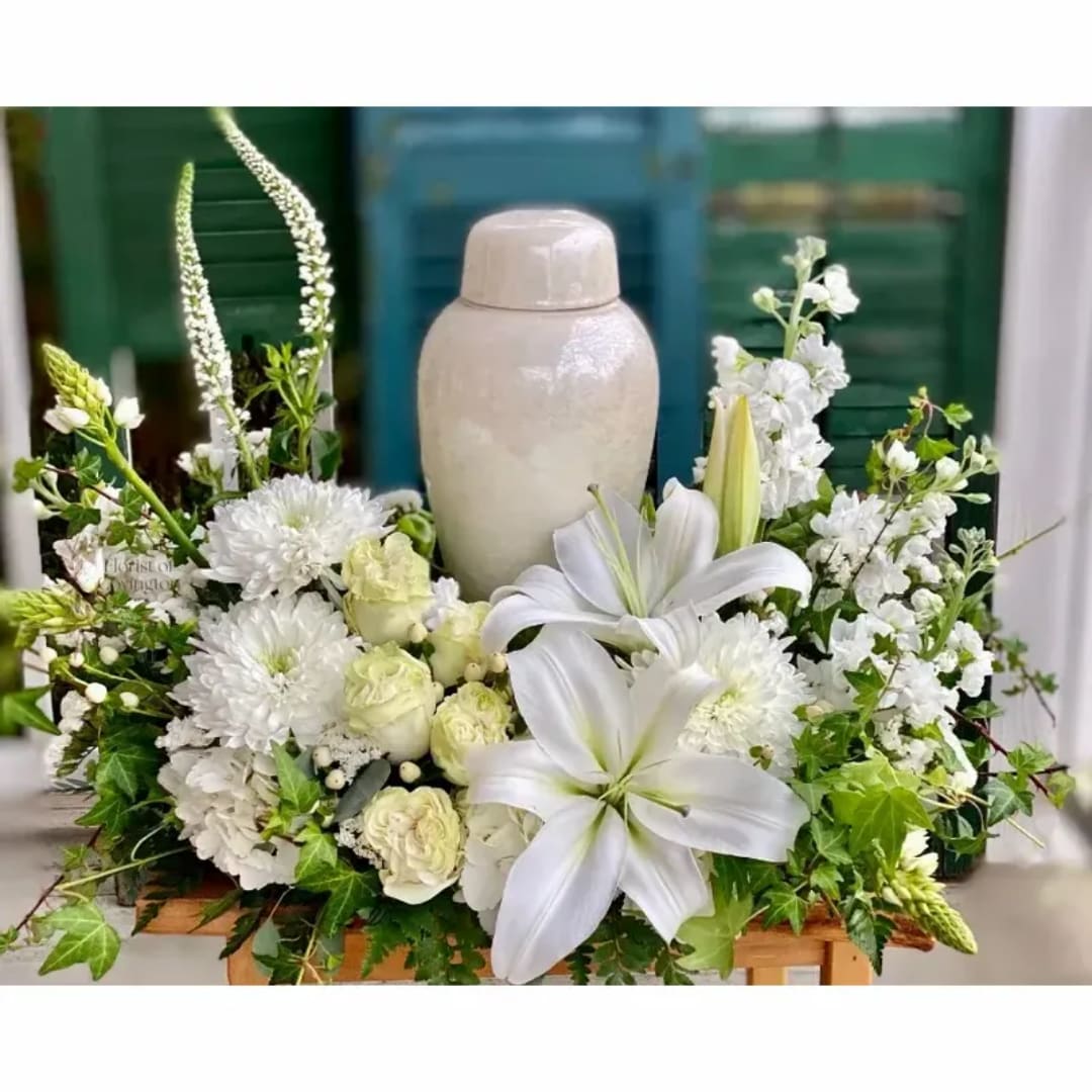 White floral arrangement with lilies, roses, and chrysanthemums around a ceramic urn