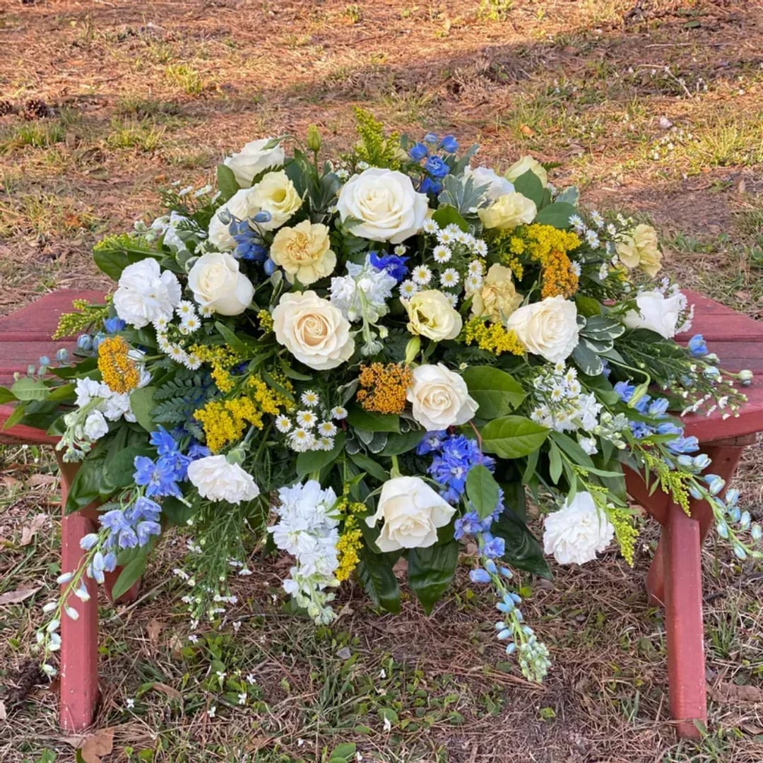 Large white and blue floral arrangement on a red bench