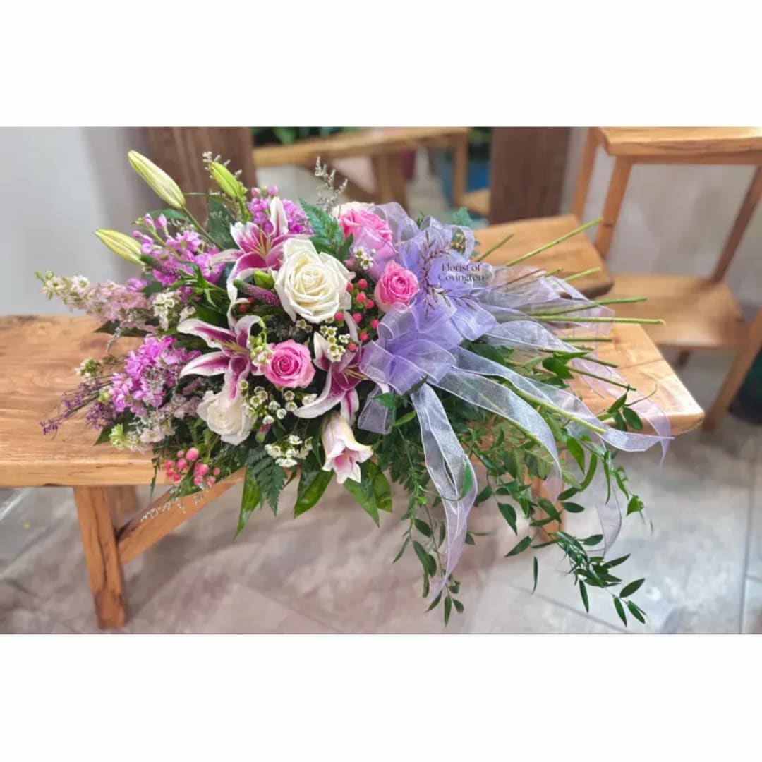 Pink and white floral bouquet with lilies and roses, tied with a lavender ribbon