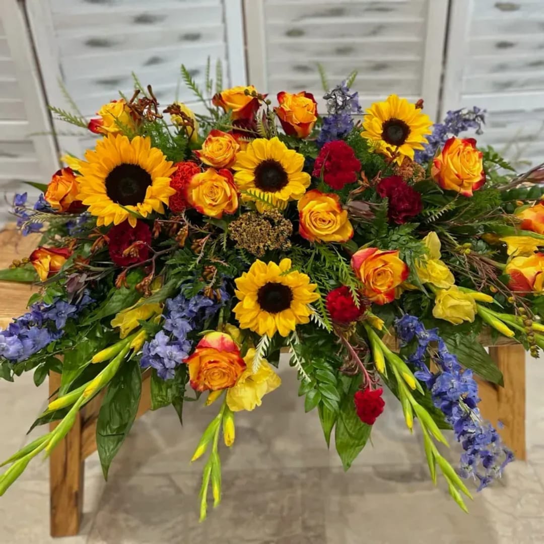 Large mixed bouquet with sunflowers, roses, and blue flowers on a table