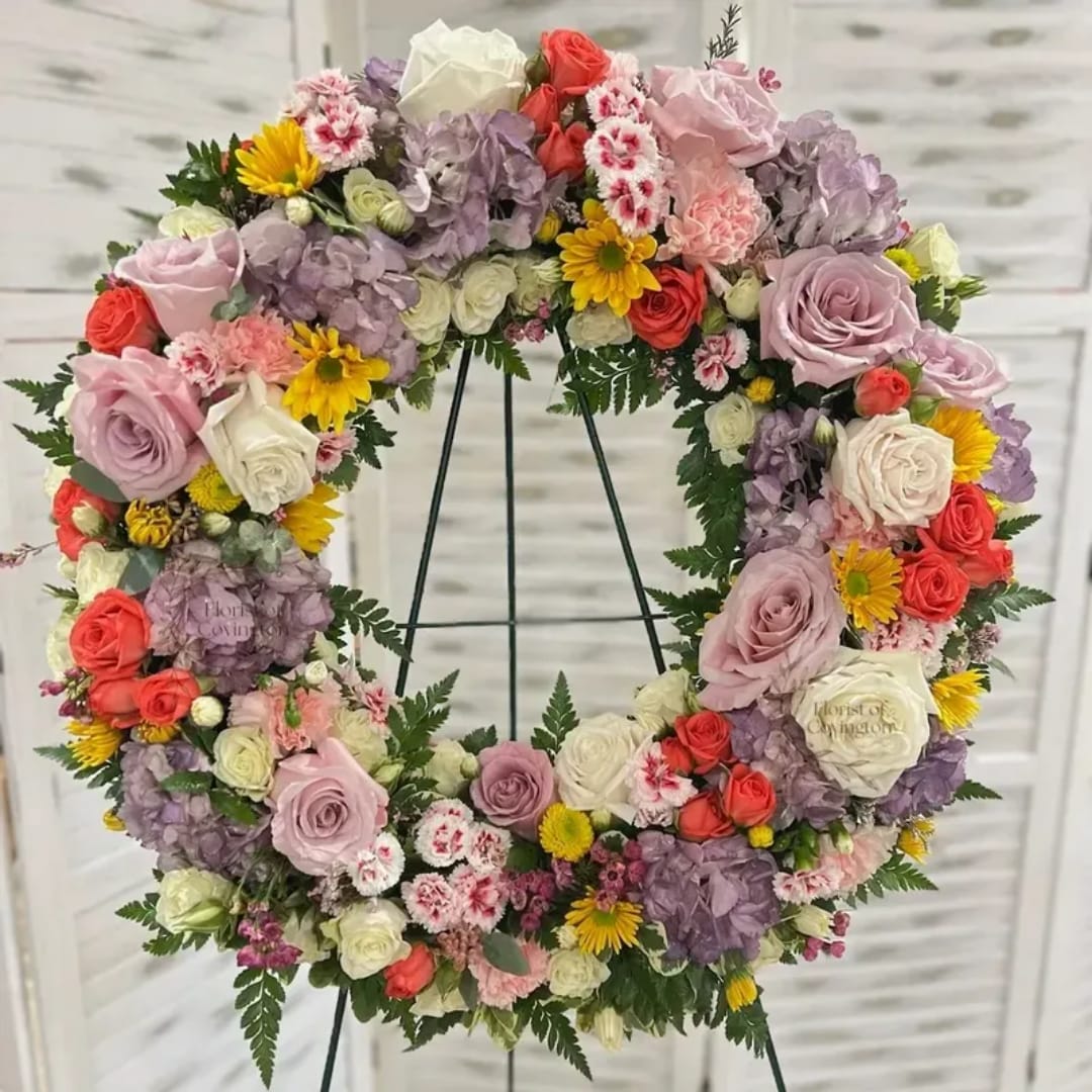 Floral wreath with roses, hydrangeas, and daisies on a stand