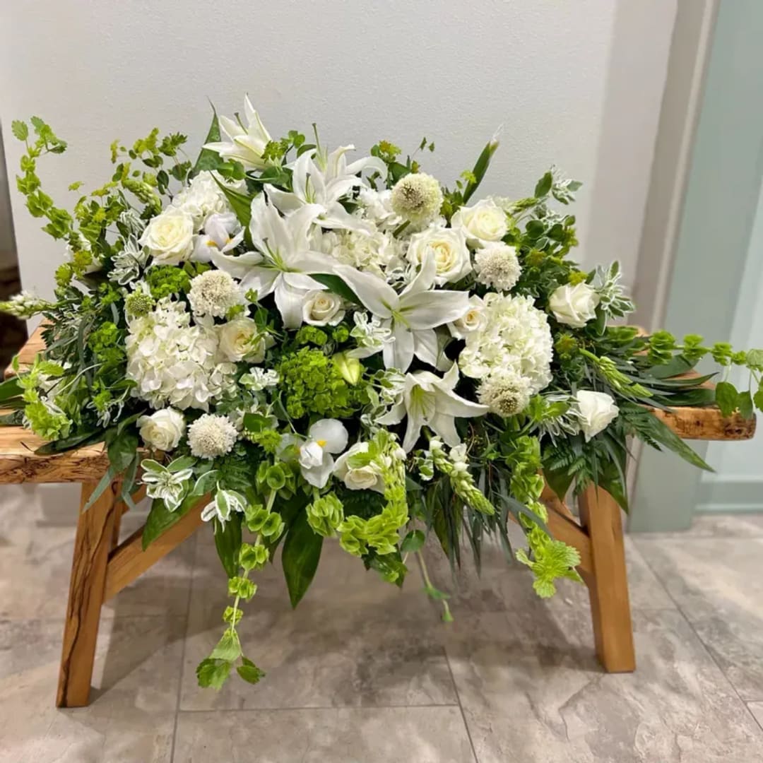 White floral arrangement with lilies and roses on a wooden stand