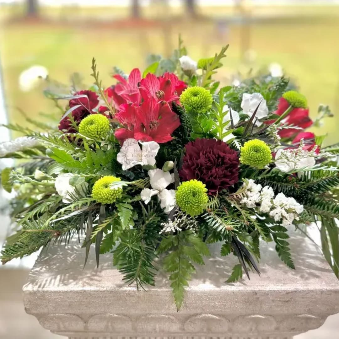 Mixed red, white, and green floral arrangement in a low stone container