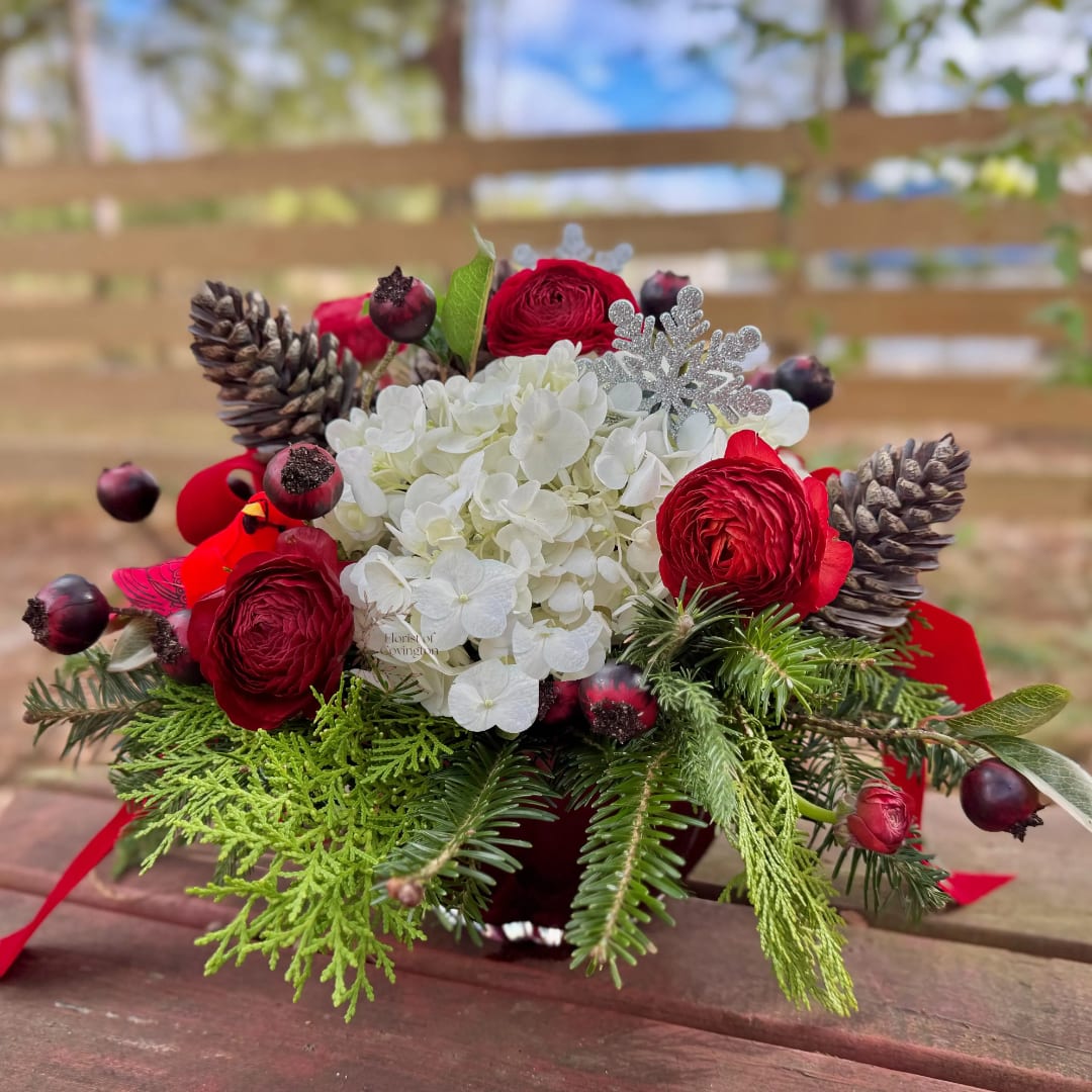 Red and white floral arrangement with pinecones in a vase