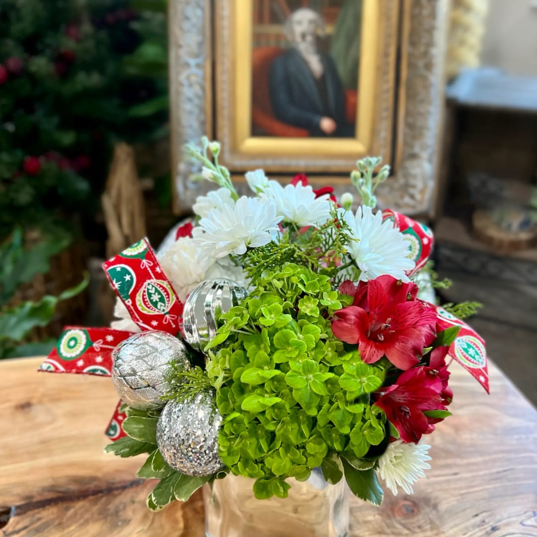 Holiday bouquet with white daisies, red flowers, and silver ornaments in a clear vase