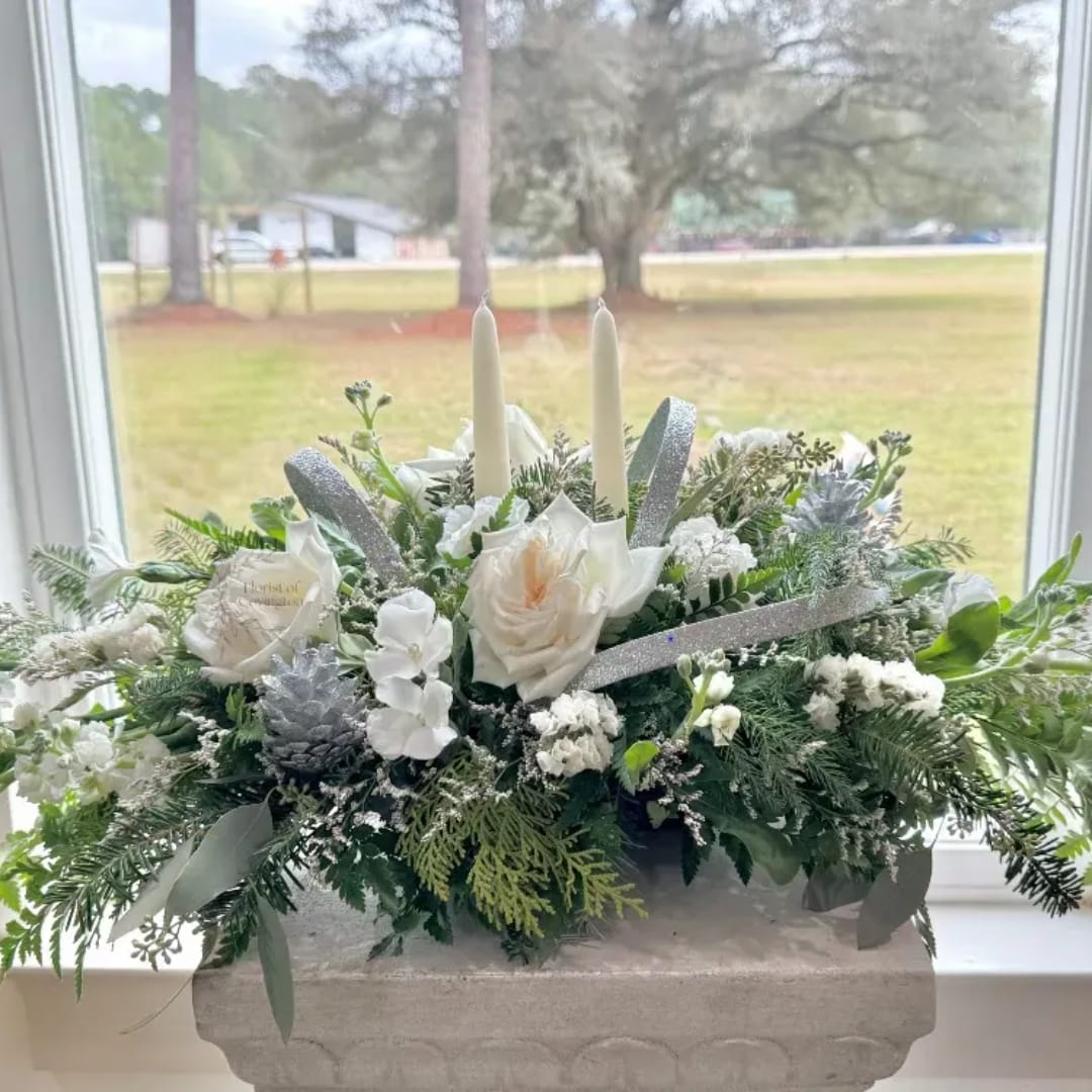 White floral centerpiece with candles and silver ribbon in a stone planter