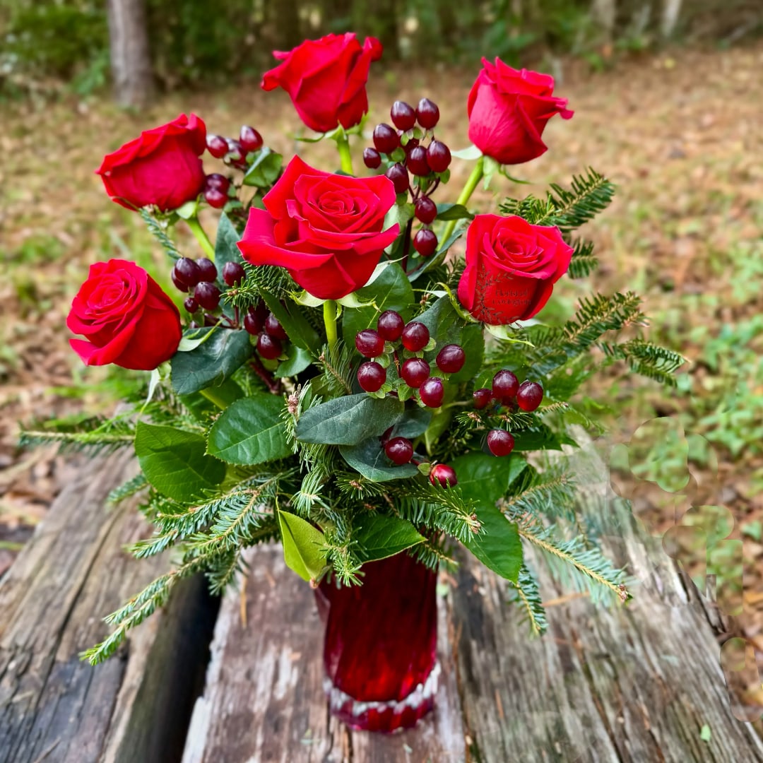 Red roses and berries in a red glass vase