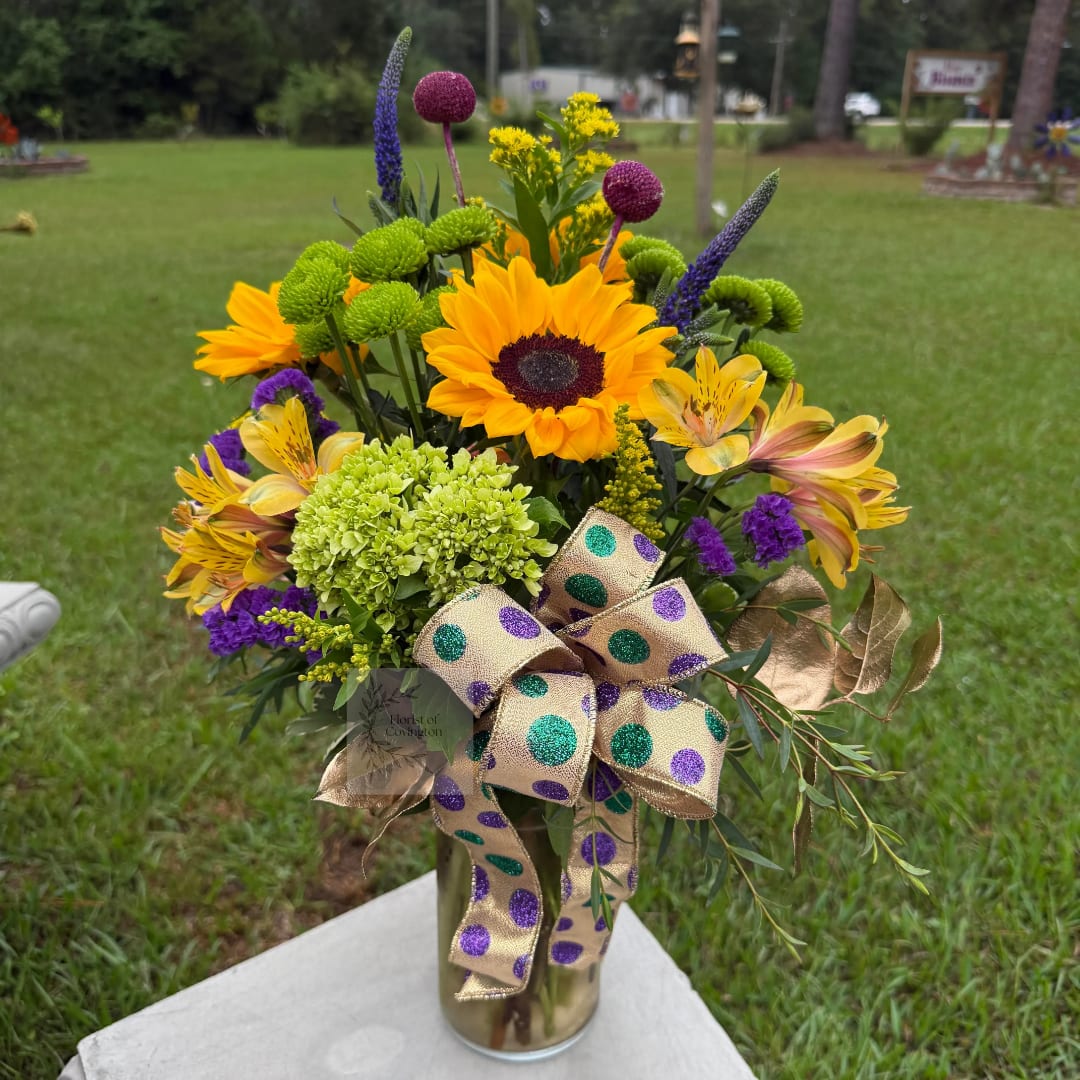 Bright mixed bouquet in a gold vase with a polka-dot ribbon