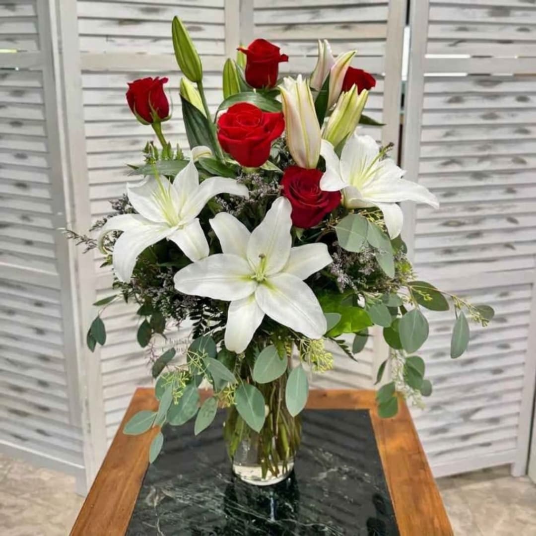 Red roses and white lilies arranged in a clear glass vase