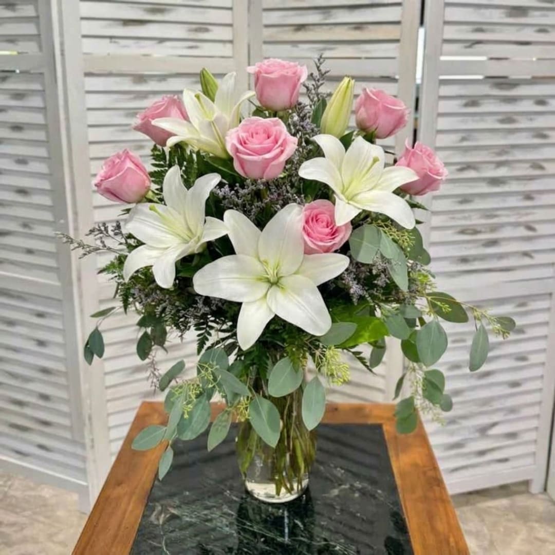 Pink roses and white lilies arranged in a clear glass vase