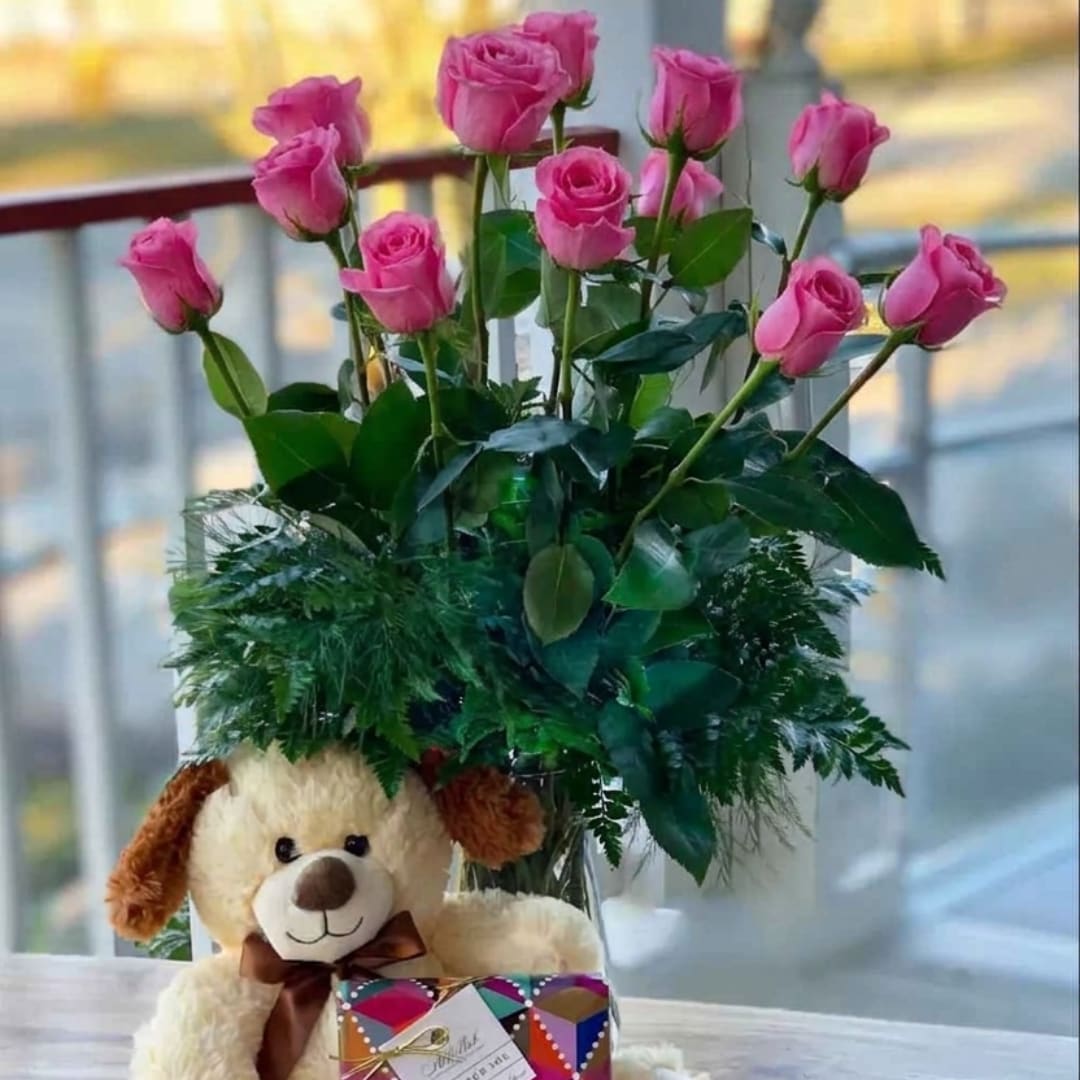 Pink roses in a vase with a teddy bear and gift box