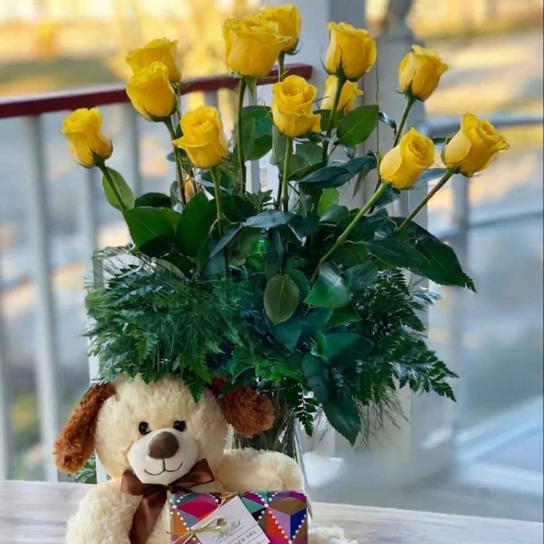 Yellow roses in a vase with a teddy bear and gift box