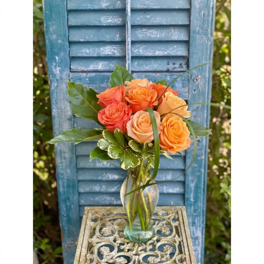 Orange and peach roses in a clear glass vase