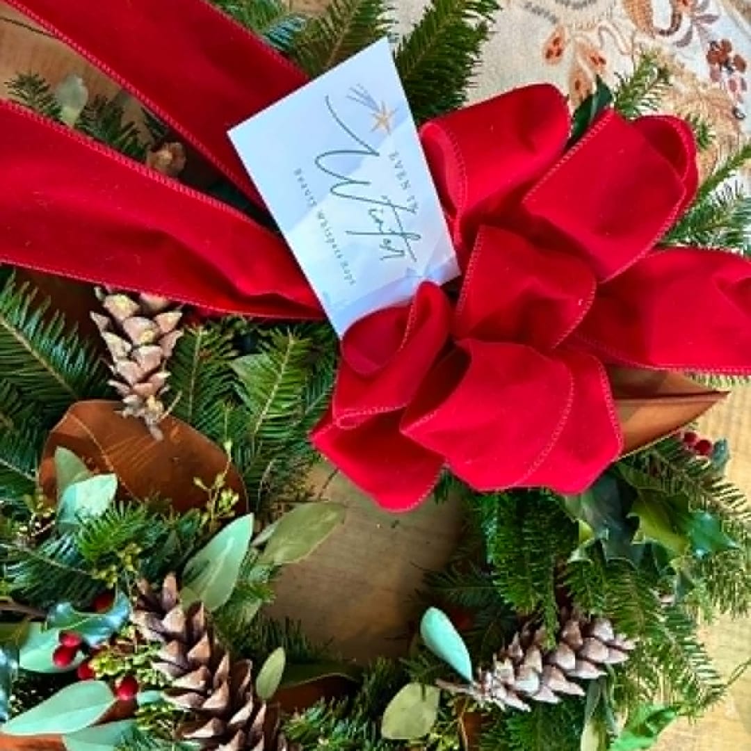 Holiday wreath with a large red bow and pinecones