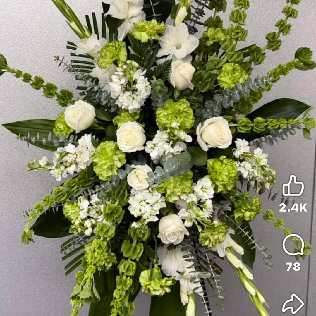 White roses and green flowers in a tall standing arrangement