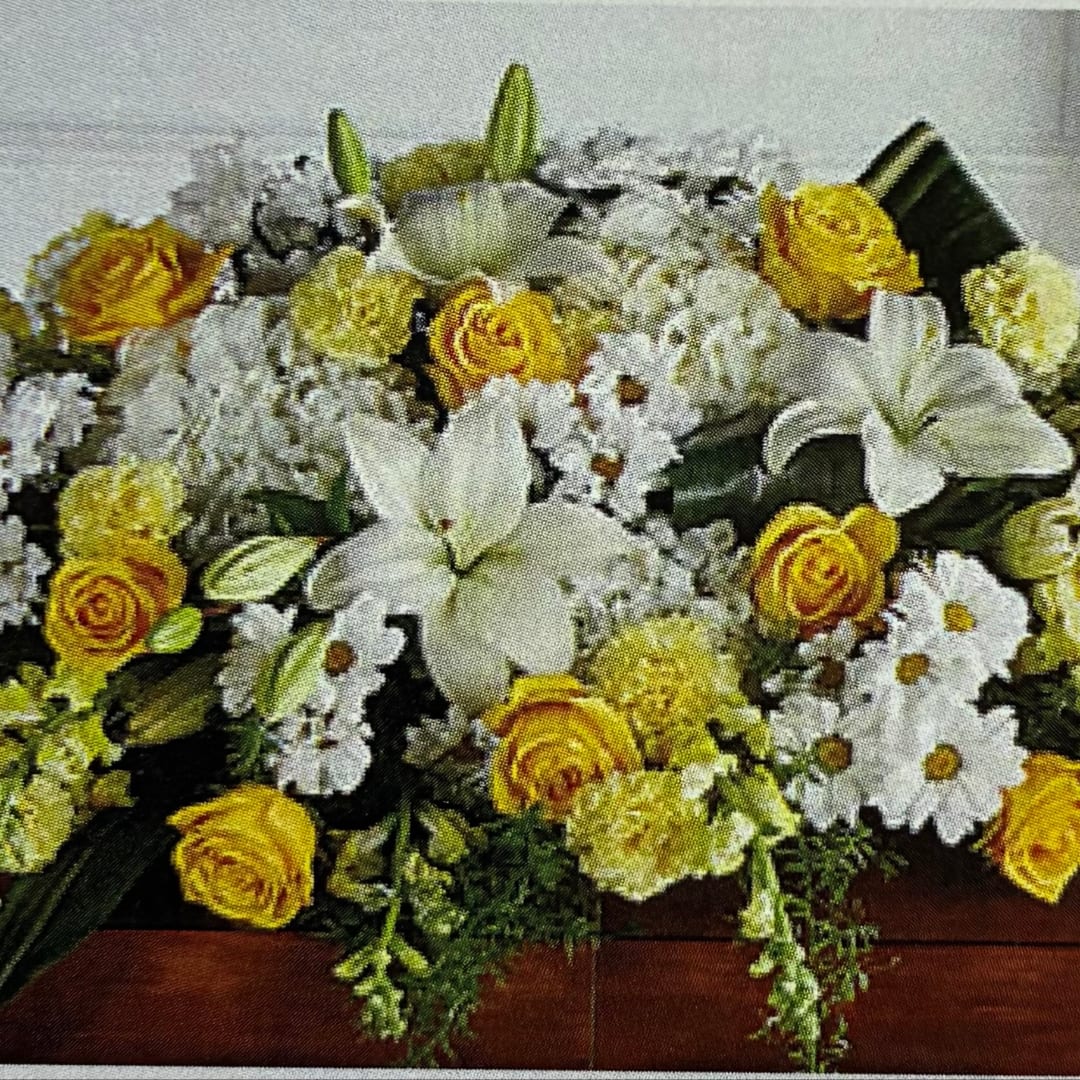 Yellow roses and white lilies arranged with white daisies in a low bouquet.