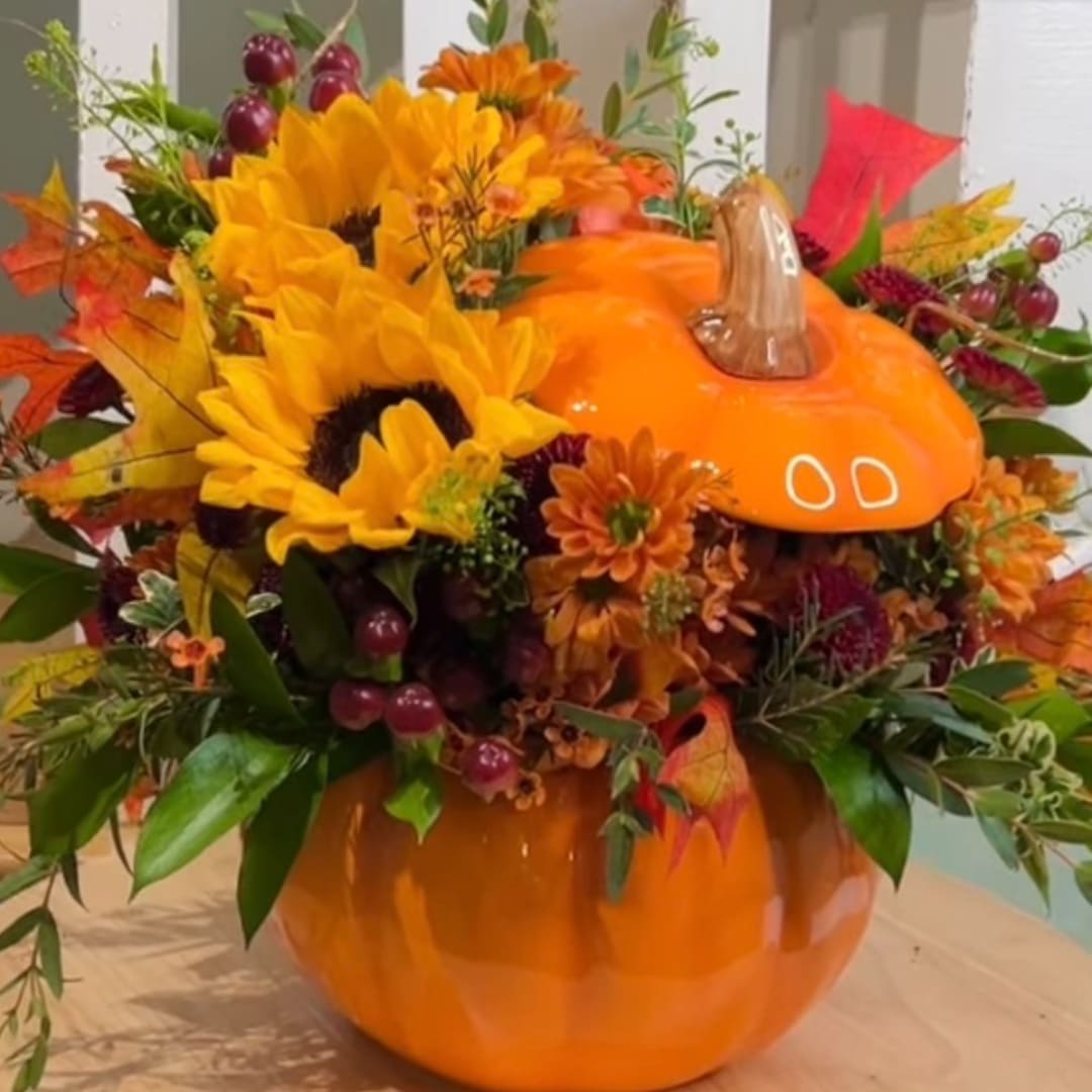 Orange pumpkin vase filled with sunflowers and autumn flowers