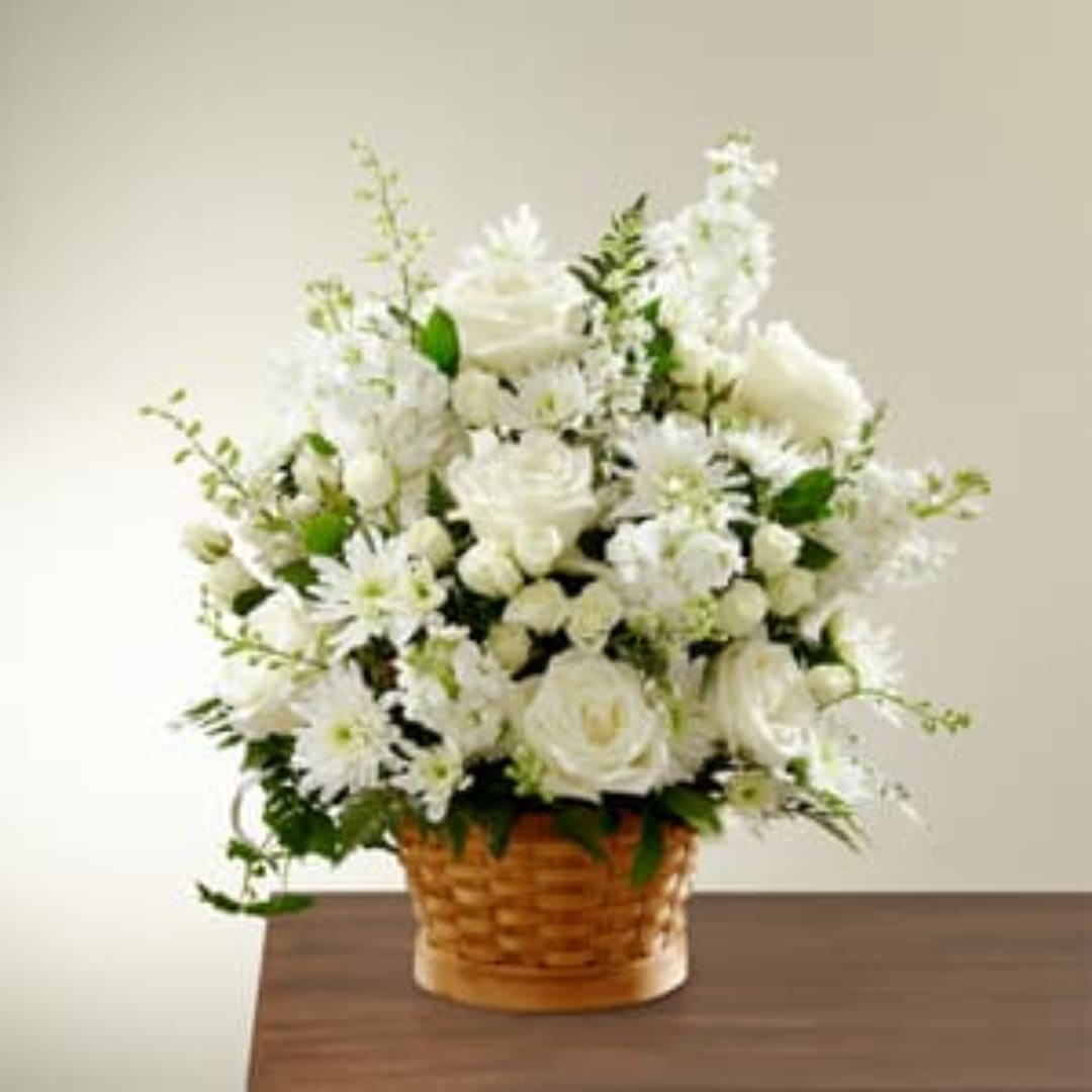 White floral arrangement in a wicker basket on a table
