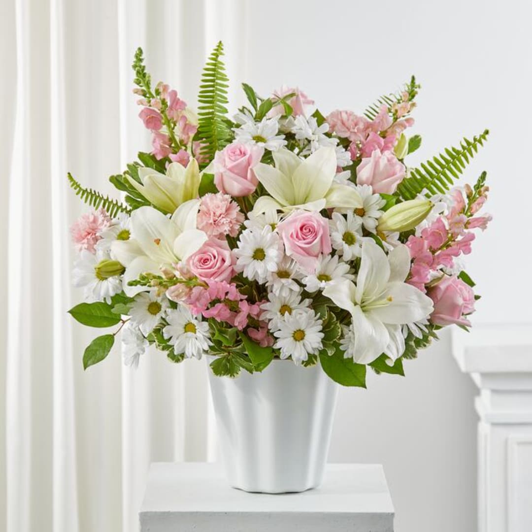 Pink and white flowers arranged in a white vase