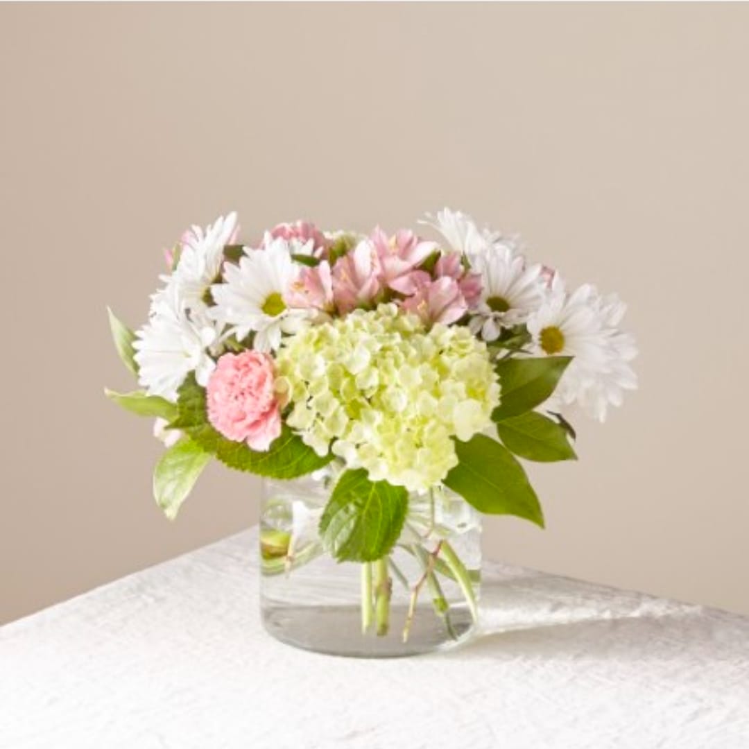 Pink and white flowers arranged in a clear glass vase
