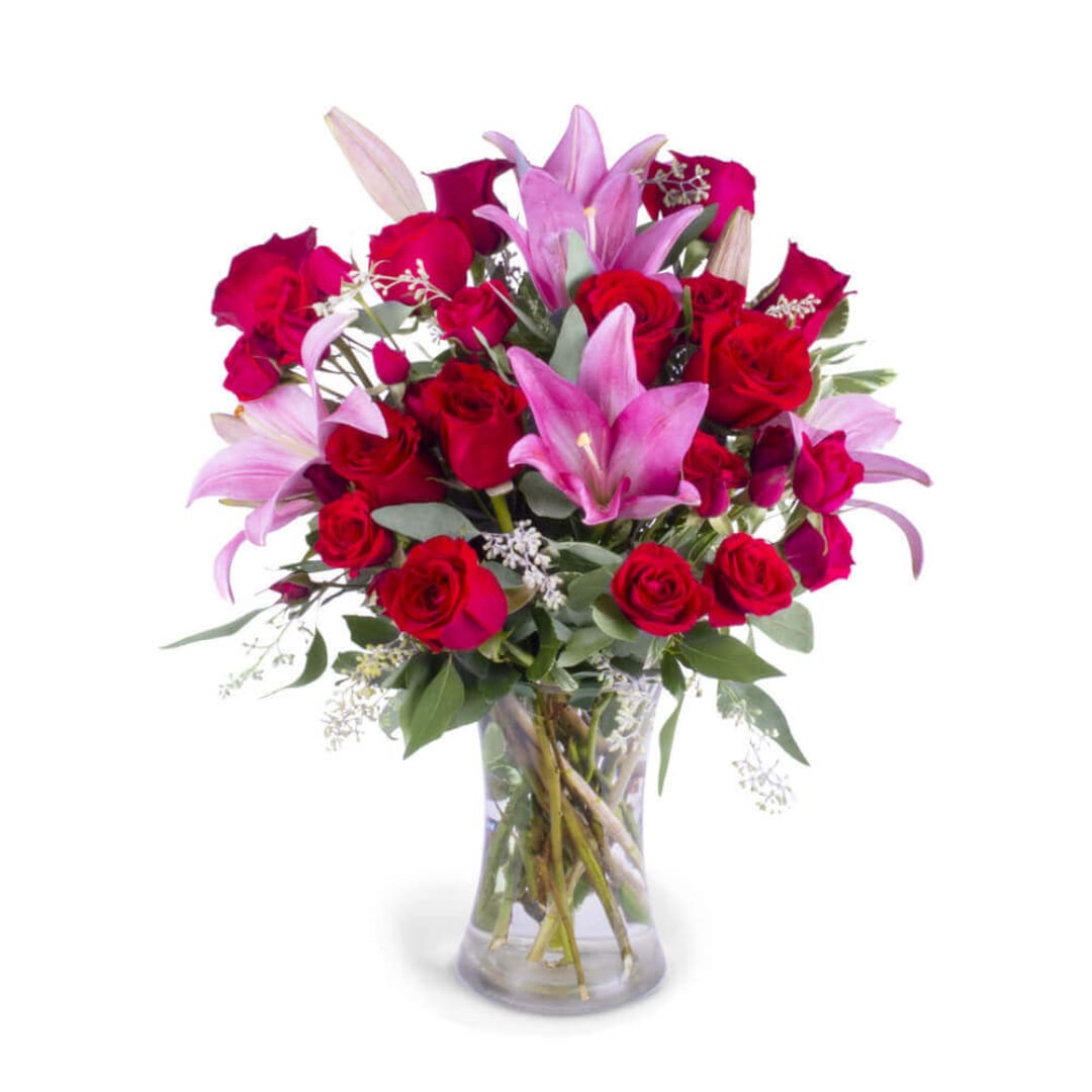 Bouquet of red roses and pink lilies in a clear glass vase