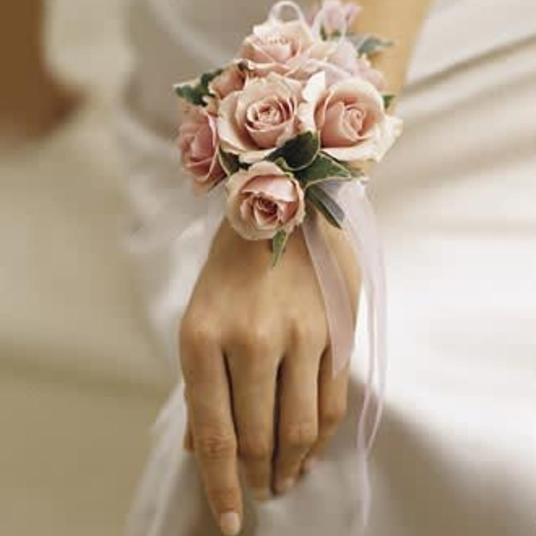 Hand wearing a pink rose wrist corsage with ribbon
