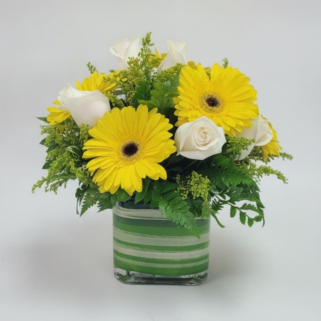 Yellow gerbera daisies and white roses in a striped glass vase