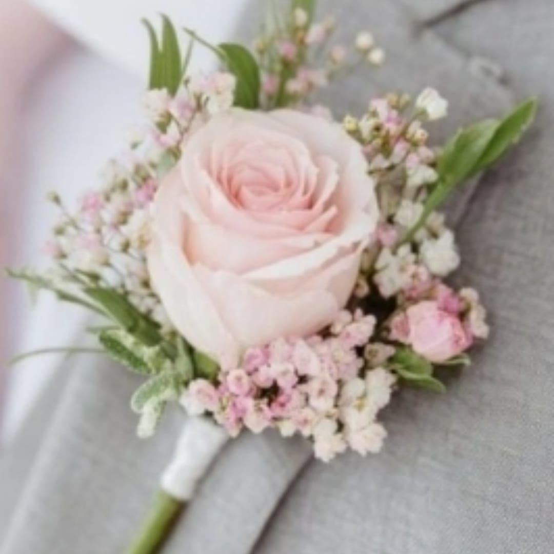 Pink rose boutonniere with small white and pink filler flowers