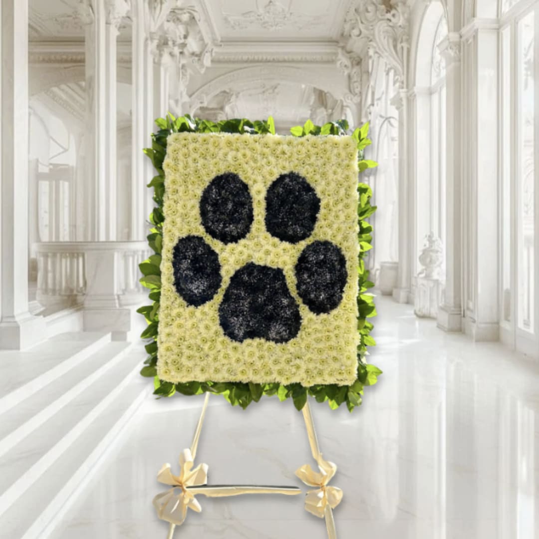 Floral standing tribute with a black paw print on a white flower panel