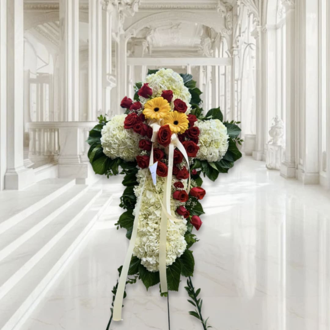 Standing floral cross with white blooms, red roses, and yellow daisies