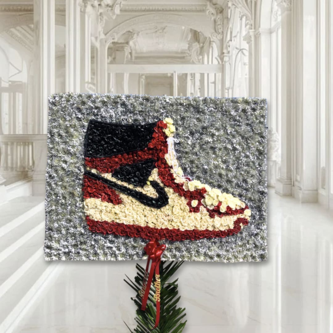 Floral tribute shaped like a sneaker on a standing display