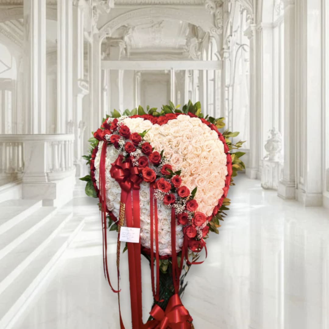 Heart-shaped rose arrangement with red ribbons in a white hall
