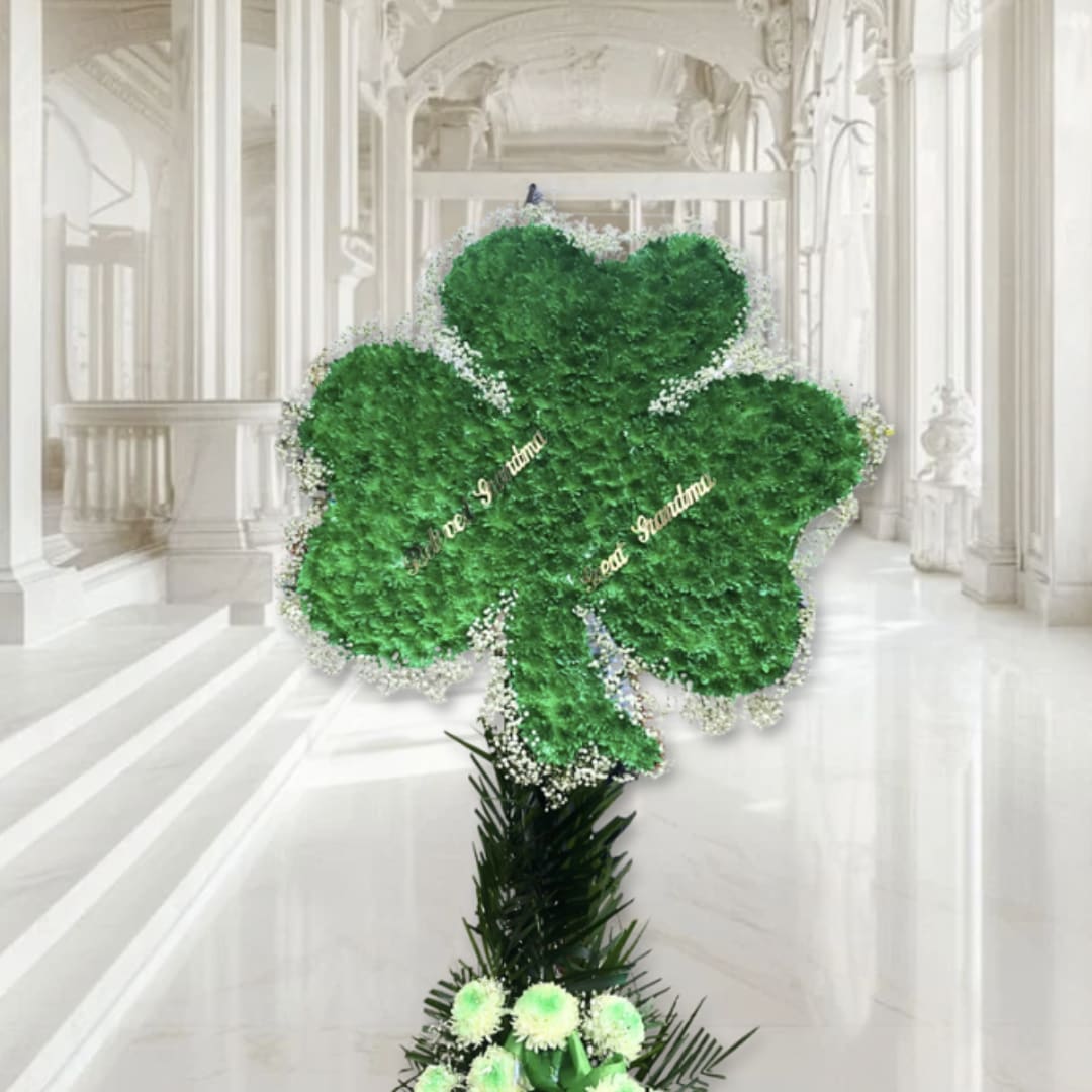 Green shamrock-shaped floral display with white accents on a tall stand
